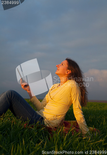 Image of Teen girl reading electronic book outdoors