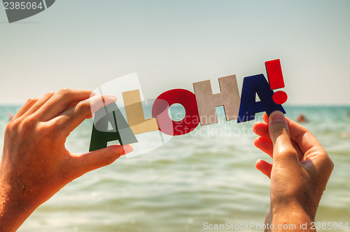 Image of Female's hand holding colorful word 'Aloha'