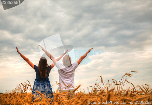 Image of Couple staying with raised hands at a wheat field