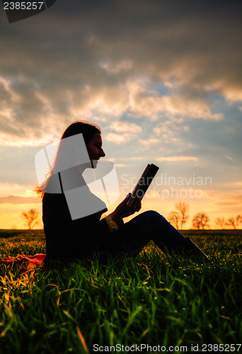Image of Teen girl reading book outdoors