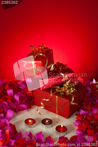 Image of Christmas gifts and candles over red background