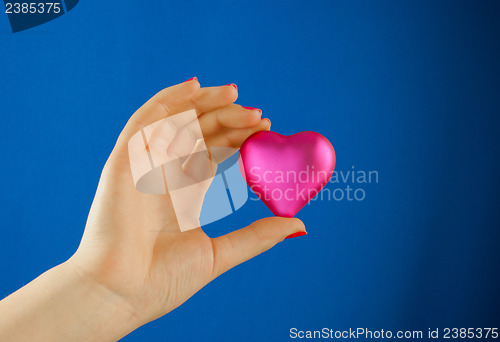 Image of Hand holds a heart shaped gift against blue background