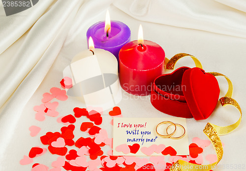 Image of Two rings and a card with marriage proposal with three candles