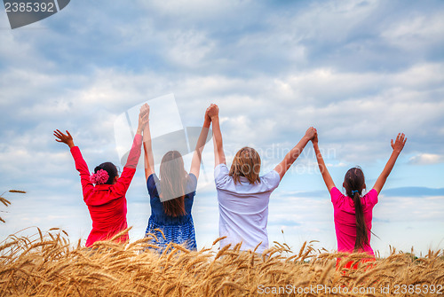 Image of Four young people staying with raised hands