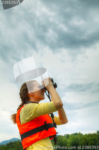 Image of Young woman looking through binoculars