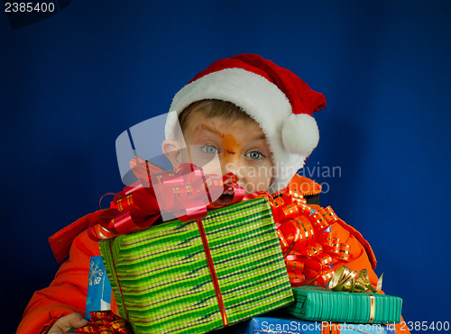 Image of Surprised boy looking from behind the Christmas presents