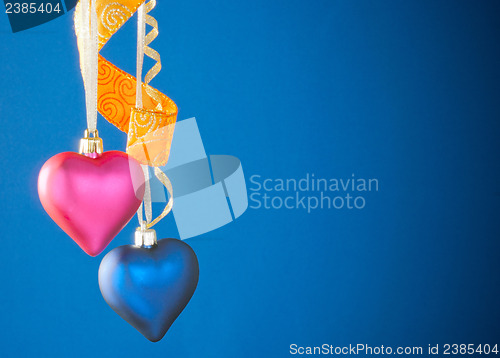 Image of Two heart shaped toys hanging against blue background