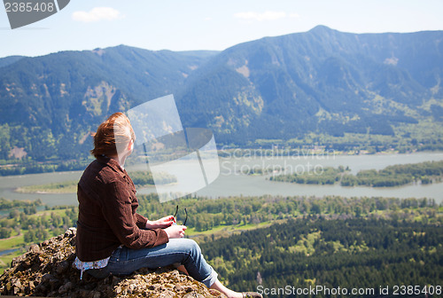 Image of Woman sits at the top of a cliff