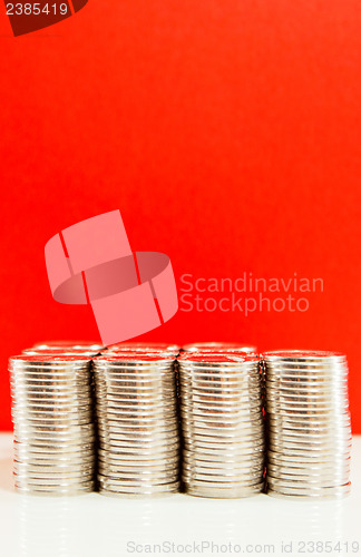 Image of Coins stacked in bars against red background