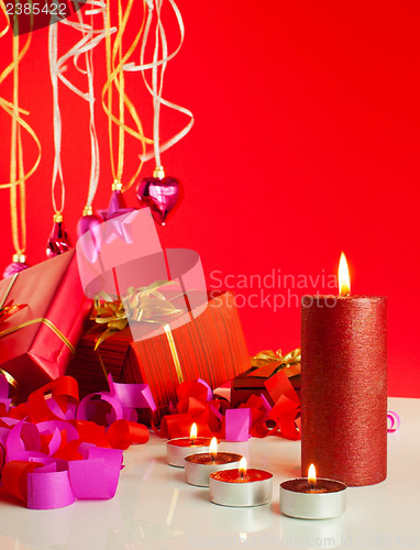 Image of Christmas gifts and candles over red background