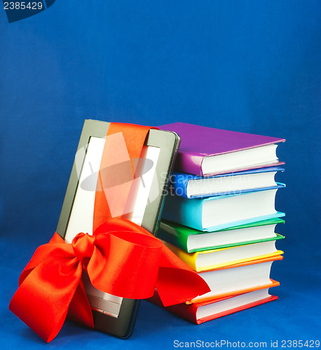 Image of Electronic book reader tied up with red ribbon with stack of books