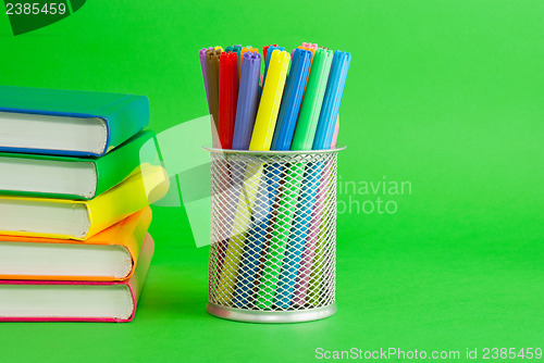 Image of Stacks of colorful books and socket with felt pens