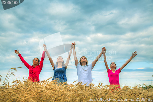 Image of Four young people staying with raised hands