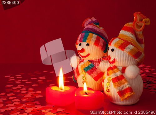Image of Two snowmen with two burning heart shaped candles