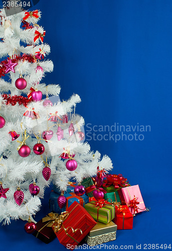 Image of Heap of the Christmas presents under decorated white evergreen t