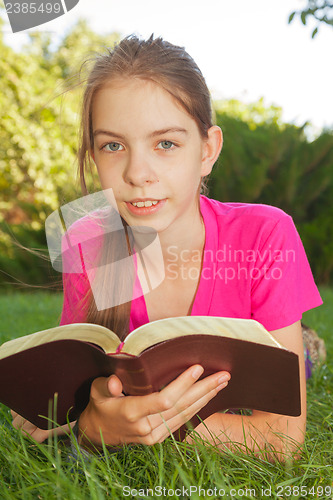 Image of Teen girl reading the Bible outdoors