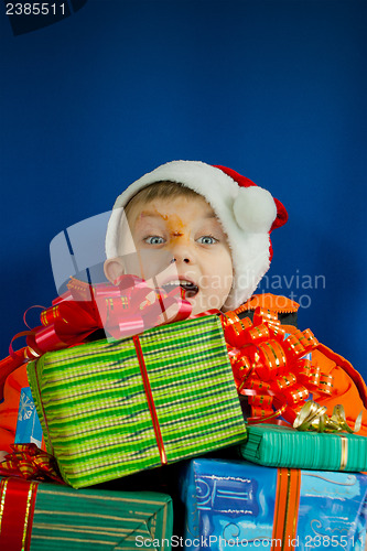 Image of Surprised boy looking from behind the Christmas presents