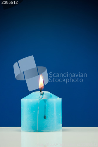 Image of Close up of burning candle against dark blue background