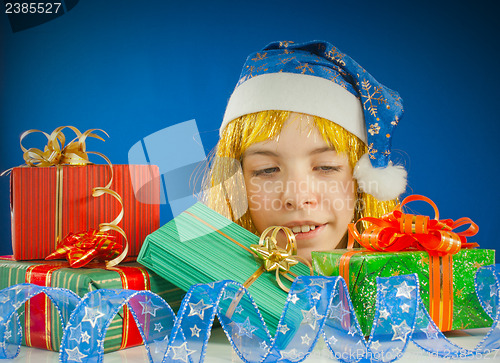 Image of Surprised teen girl looking from behind the Christmas presents