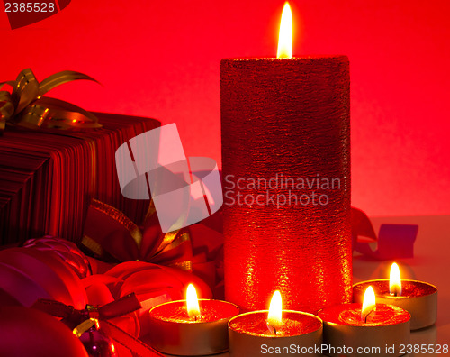 Image of Candles and gifts over red background