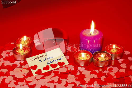 Image of Two rings and a card with marriage proposal with six candles