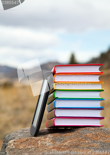 Image of Stack of printed books with electronic book reader