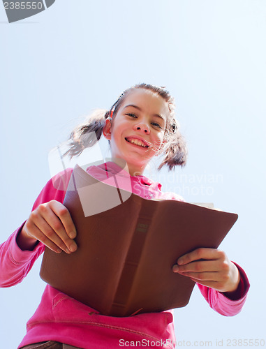 Image of Tenn girl reading the Bible against blue sky