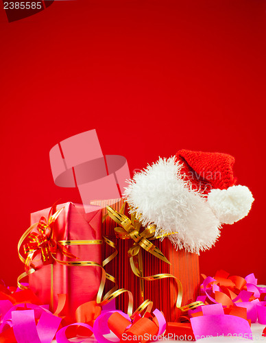 Image of Christmas presents with Santa's hat against red background