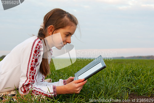 Image of Teen girl with electronic book laying on grass