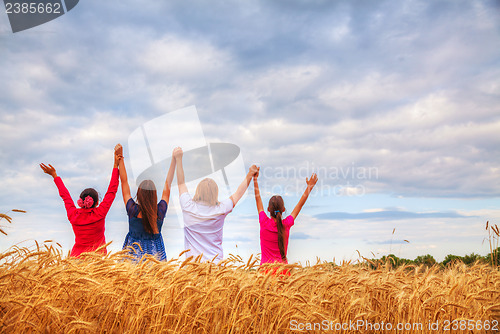 Image of Four young people staying with raised hands
