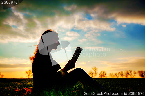 Image of Teen girl reading book outdoors