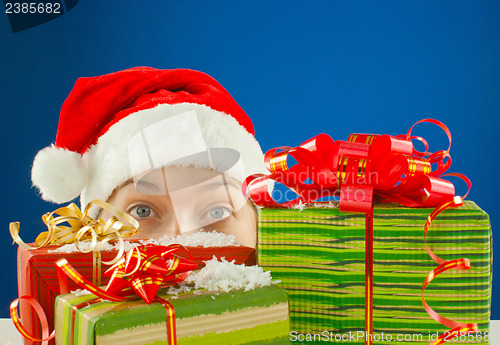 Image of Surprised teen girl looking from behind the Christmas presents