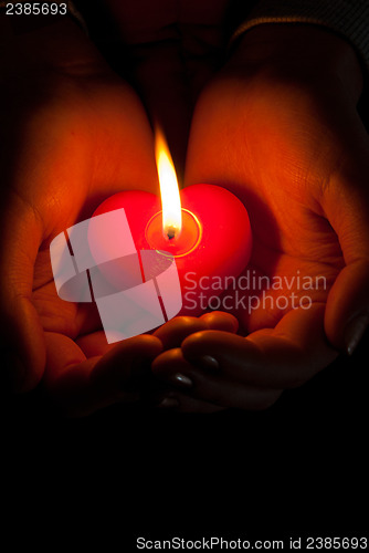 Image of Human hands hold heart shaped burning candle