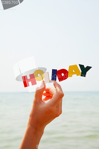 Image of Female's hand holding colorful word 'Holiday'