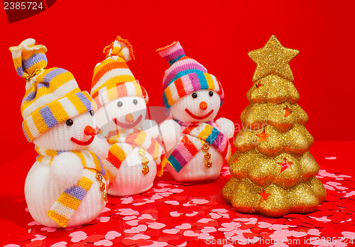 Image of Three snowmen with golden evergreen tree