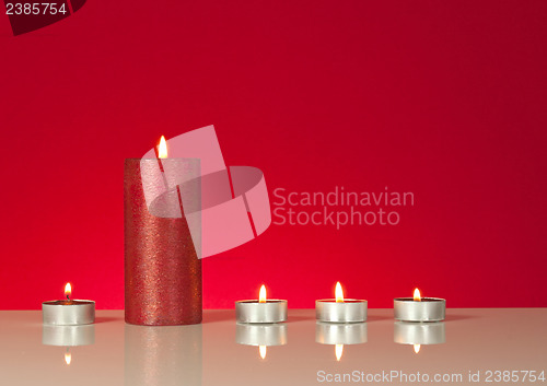 Image of Five burning candles over red background