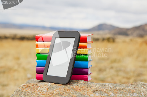 Image of Stack of printed books with electronic book reader