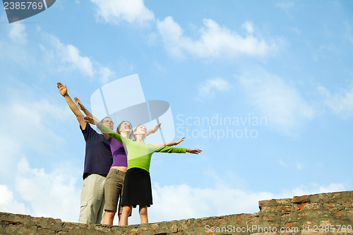 Image of Three young people staying with raised hands