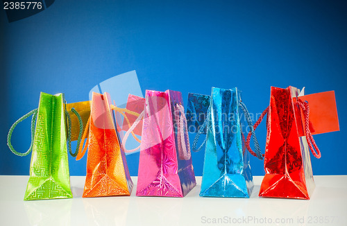 Image of Row of colorful bags against blue background