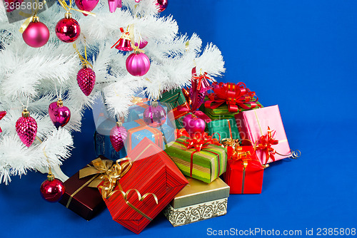Image of Heap of the Christmas presents under decorated white evergreen t