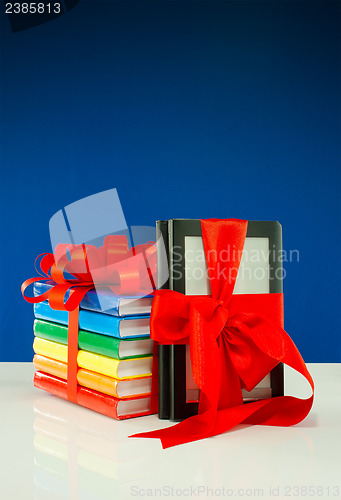 Image of Books tied up with ribbon and electronic book reader against blue background