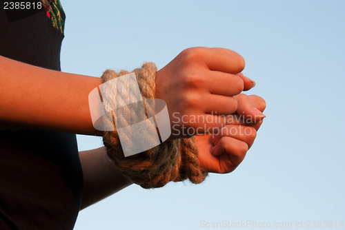 Image of Hands tied up with rope against blue sky