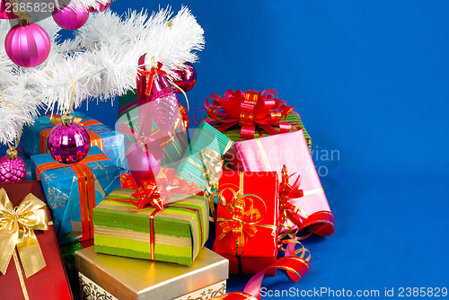Image of Heap of the Christmas presents under decorated white evergreen t