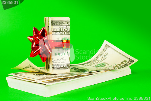 Image of Roll of US dollars tied up with ribbon on the stack of bills