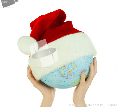 Image of Hands holds globe with Santa's hat over white background