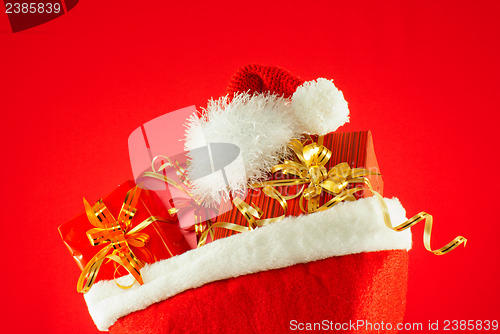 Image of Christmas presents with Santa's hat against red background