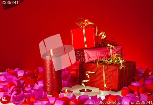 Image of Christmas gifts and candles over red background