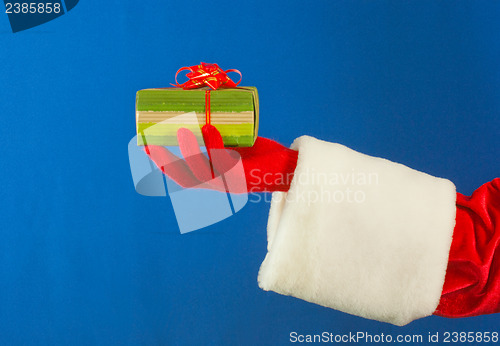 Image of Santa's hand holding a present over blue background