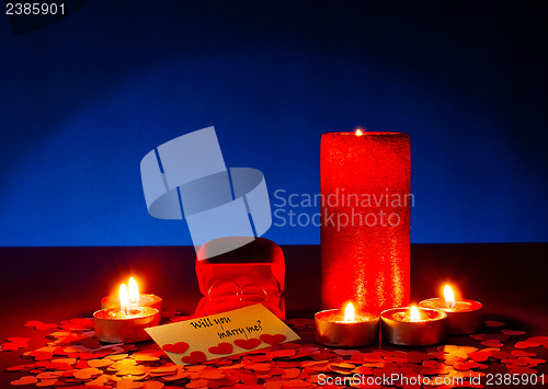 Image of Two rings and a card with marriage proposal with six candles