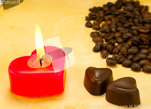 Image of Burning candle, two heart shaped candies and cofee beans